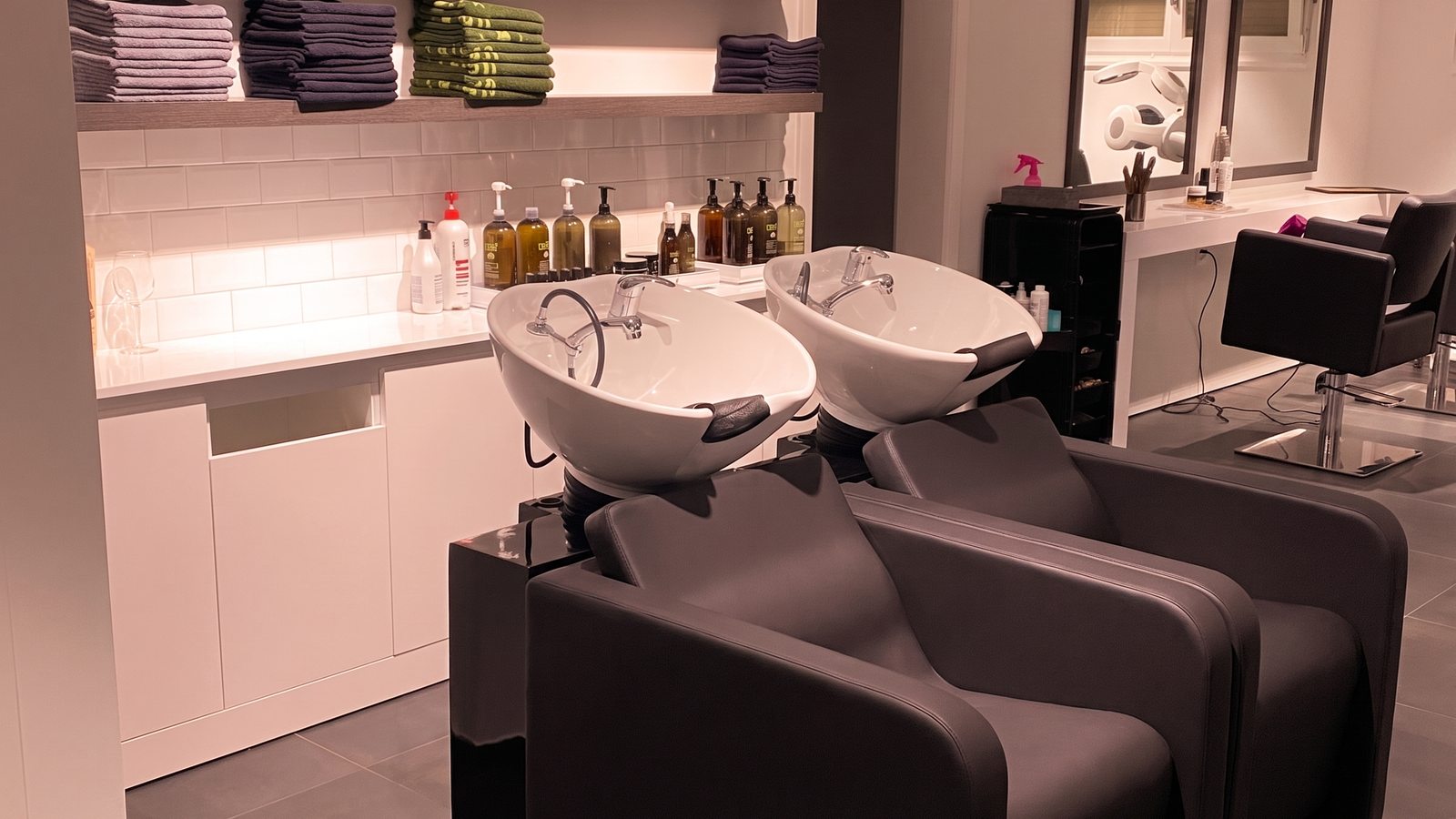 Vue d'ensemble des bacs à shampooing, mobilier noir et lumière chaude