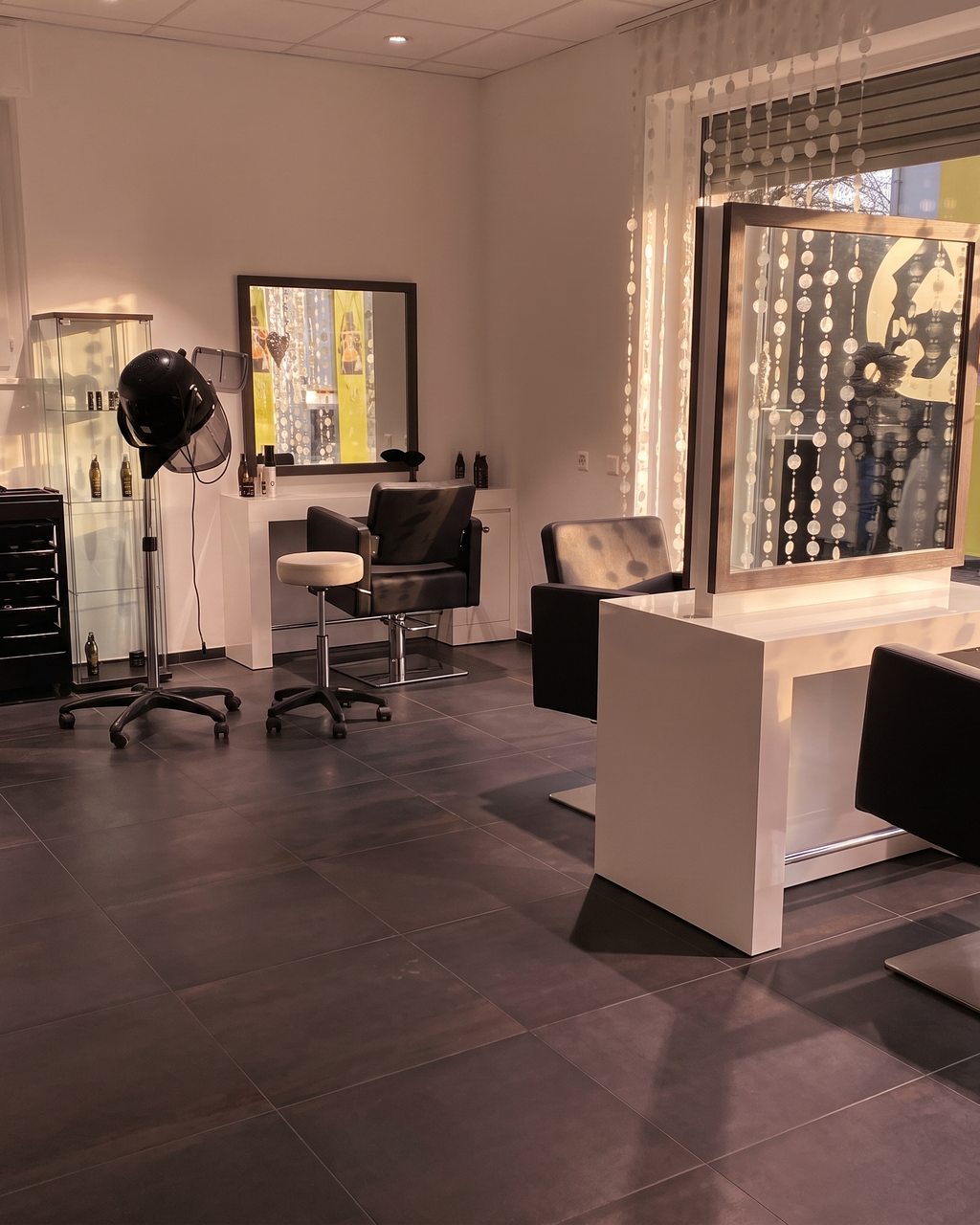 Intérieur du salon Fémina Coiffure : bacs à shampooing sur fond de mobilier noir et lumière dorée